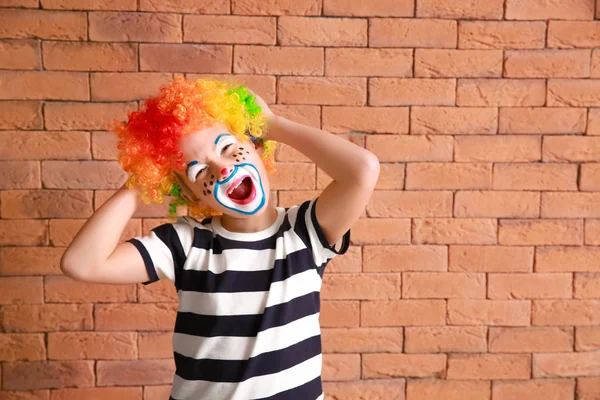 Söt liten pojke med clown smink mot tegel vägg. April dårar dag firande — Stockfoto