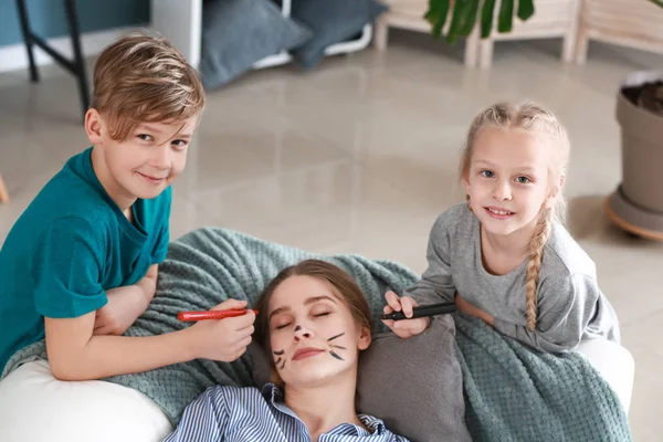 Kleine Kinder zeichnen das Gesicht ihrer schlafenden Mutter. Aprilscherz — Stockfoto