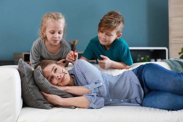 Des petits enfants dessinent sur le visage de leur mère qui fait semblant de dormir. Plaisanterie de la journée des fous d'avril — Photo