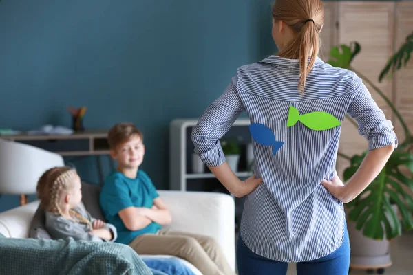 Mother with paper fish on her back scolding children. April fools' day prank — Stock Photo, Image