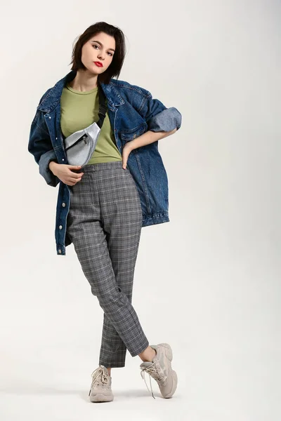 Szép fiatal nő modern stílusos ruhákat világos háttér — Stock Fotó