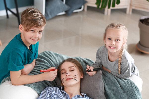 Little children drawing on face of their sleeping mother. April fools' day prank Stock Photo