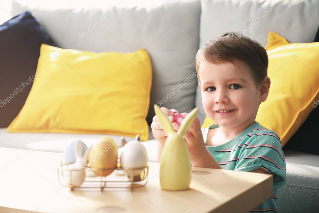Cute little boy at table with Easter eggs