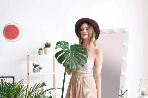 Portret van mooie vrouw met groene tropische blad binnenshuis — Stockfoto