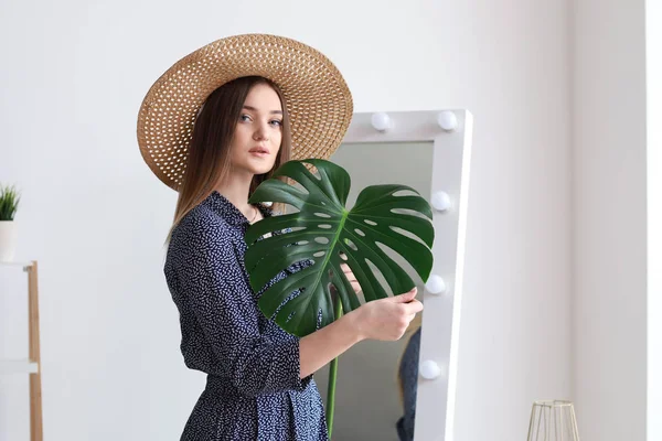 Portrait of beautiful woman with green tropical leaf indoors — Stock Photo, Image