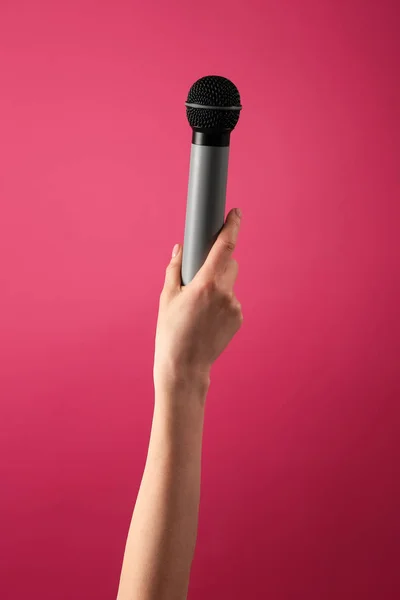 Női kéz mikrofonnal a színes háttéren — Stock Fotó