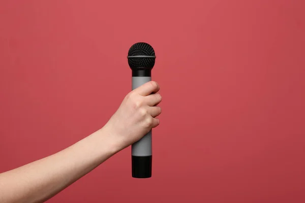 Женская рука с микрофоном на цветном фоне — стоковое фото