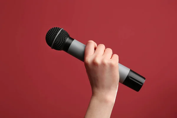 Mano femminile con microfono su sfondo a colori — Foto Stock