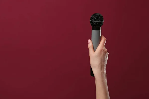 Mano femminile con microfono su sfondo a colori — Foto Stock