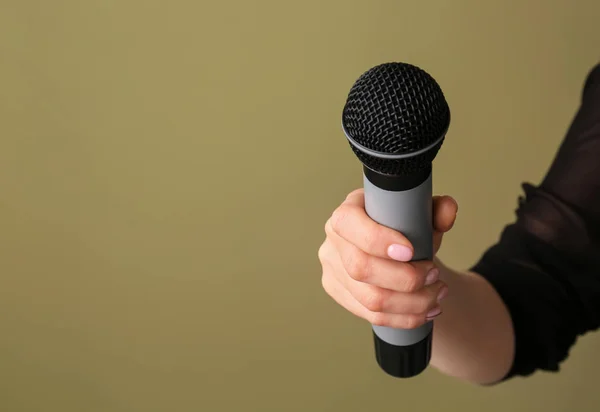 Female hand with microphone on color background — Stock Photo, Image