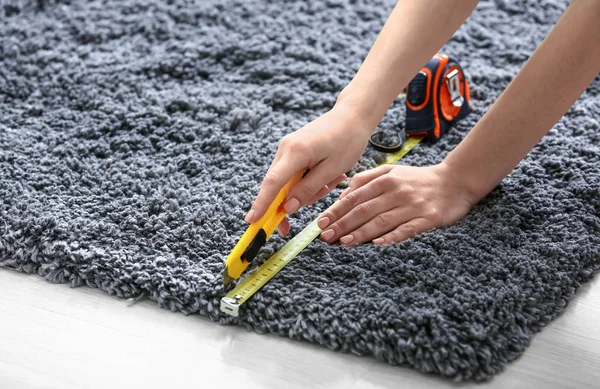 Kobieta z taśmą środek cięcia dywan na podłodze — Zdjęcie stockowe