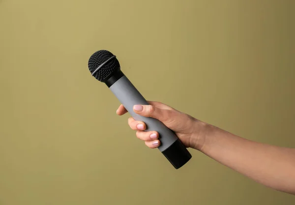 Mano femminile con microfono su sfondo a colori — Foto Stock