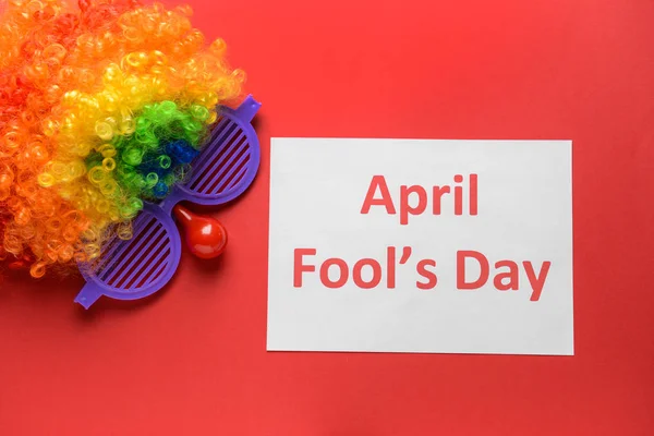 Party decor and paper sheet with text APRIL FOOL'S DAY on color background — Stock Photo, Image