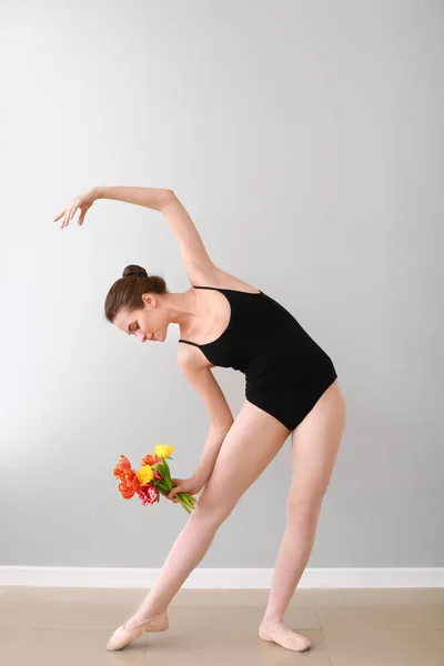 Mooie jonge ballerina met boeket bloemen in dansstudio — Stockfoto