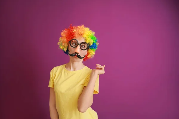 Lustige Frau mit Party-Dekor für den Aprilscherz auf farbigem Hintergrund — Stockfoto