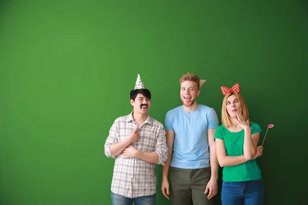 Funny friends with party decor for April Fools\' Day on color background