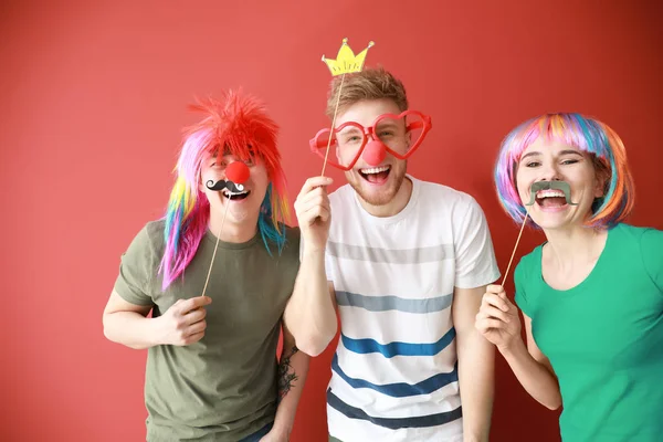 Amigos divertidos con decoración de fiesta para el día de los tontos de abril en el fondo de color —  Fotos de Stock