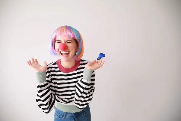 Funny woman with party whistle for April Fools' Day prank on light background — Stock Photo, Image