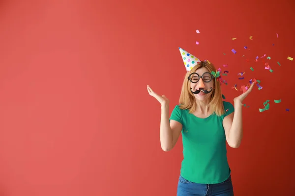 Funny woman with party decor and confetti for April Fools' Day on color background — Stock Photo, Image