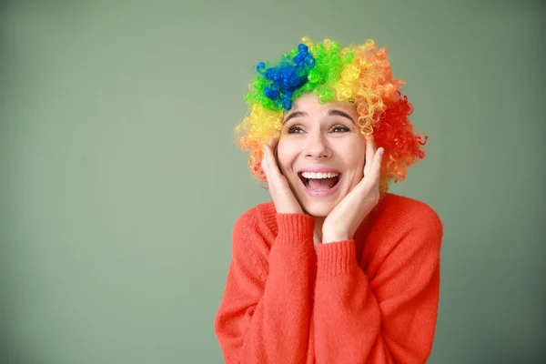 Grappige vrouw met pruik voor april Fools ' dag viering op kleur achtergrond — Stockfoto