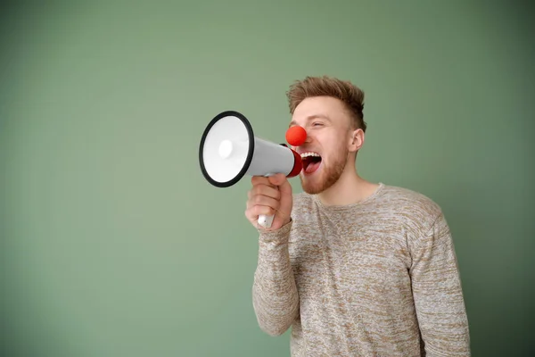Funny man with megaphone on color background. April Fools' Day prank — Stock Photo, Image