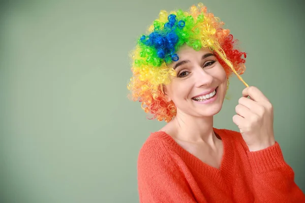Grappige vrouw met pruik voor april Fools ' dag viering op kleur achtergrond — Stockfoto
