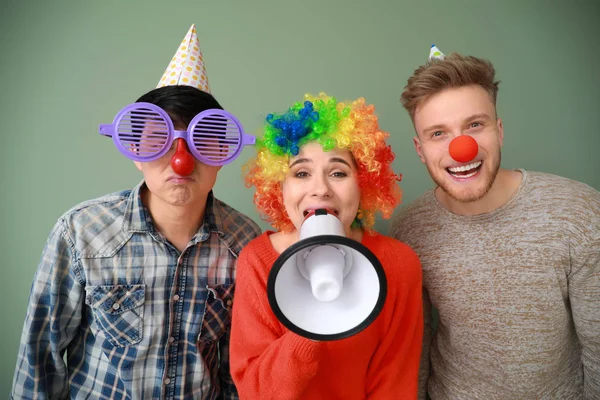 Funny friends with megaphone on color background. April Fools' Day prank — Stock Photo, Image