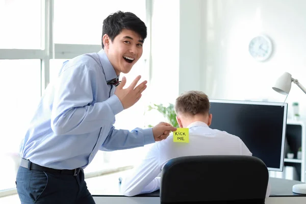 Aziatische man het spelen van een grap op zijn collega in het kantoor. April Fools ' dag prank — Stockfoto