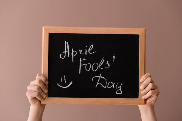 Male hands holding chalkboard with text APRIL FOOL'S DAY on color background Royalty Free Stock Photos