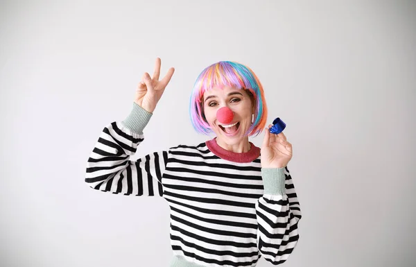 Funny woman with party whistle for April Fools' Day prank on light background — Stock Photo, Image