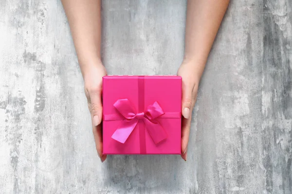 Grunge arka planda hediye kutusu ile kadın eller