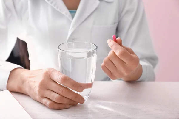 Doctor with pill and glass of water at table — Stock Photo, Image