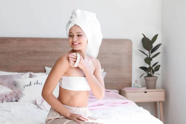 Mooie jonge vrouw met massage borstel in slaapkamer — Stockfoto