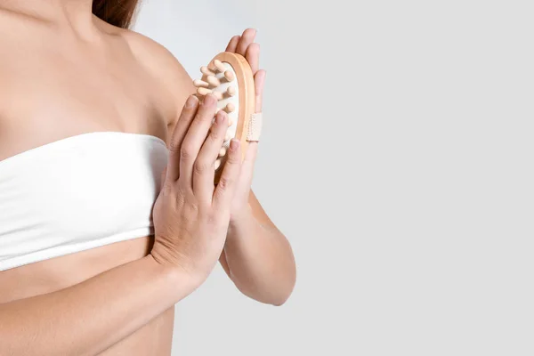 Beautiful young woman with massage brush on light background, closeup — Stock Photo, Image