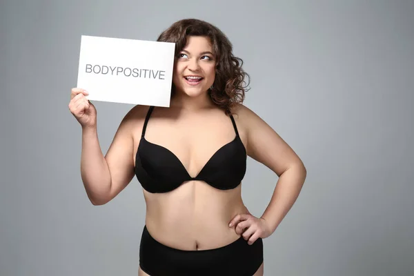 Além de tamanho mulher segurando papel com texto BODYPOSITIVE no fundo cinza — Fotografia de Stock