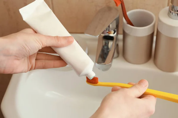 Mujer exprimiendo pasta de dientes en el cepillo en el baño, primer plano —  Fotos de Stock