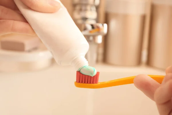 Woman squeezing toothpaste on brush in bathroom, closeup — Stock Photo, Image