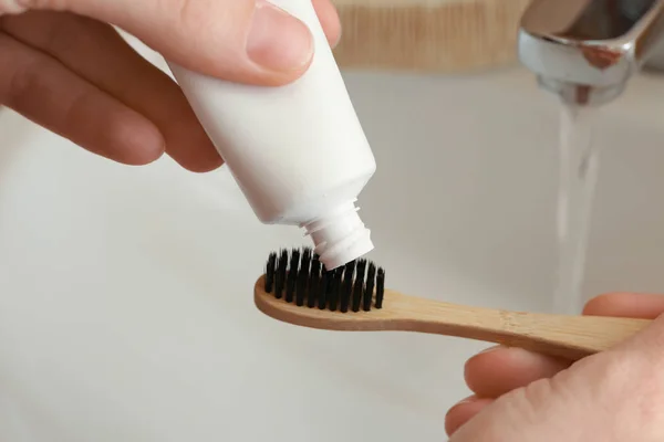 Woman squeezing toothpaste on brush in bathroom, closeup — Stock Photo, Image