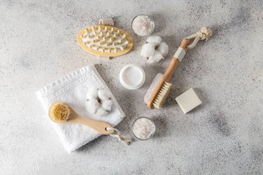 Havlu ve gri arka plan üzerinde kozmetik masaj fırçalar