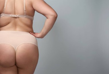 Gri arka planda şişman bir kadın.