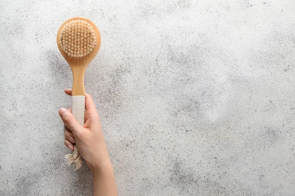 Mano femenina con cepillo de masaje sobre fondo gris — Foto de Stock