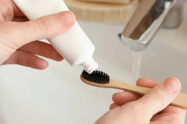 Woman squeezing toothpaste on brush in bathroom, closeup — Stock Photo, Image