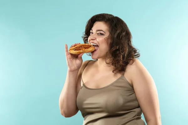 Mulher com excesso de peso com sanduíche no fundo de cor — Fotografia de Stock