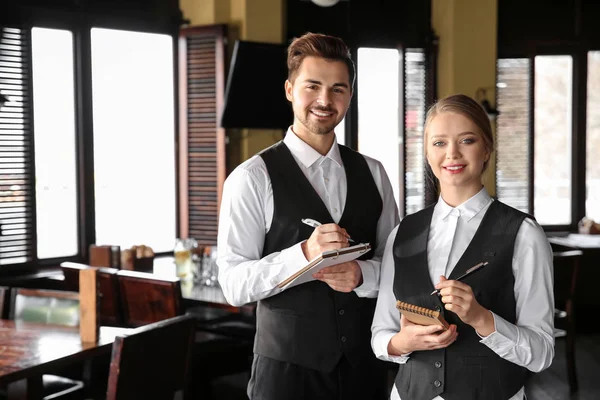 Jóvenes camareros con cuadernos en el restaurante — Foto de Stock
