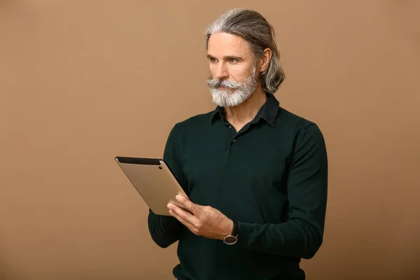 Knappe rijpe zakenman met tablet pc op kleur achtergrond — Stockfoto