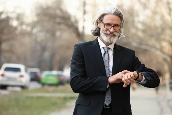 Handsome mature businessman looking at watch outdoors — Stock Photo, Image