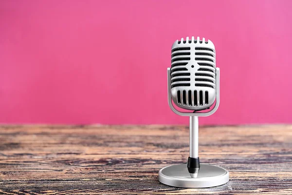 Retro microphone on table against color background — Stock Photo, Image