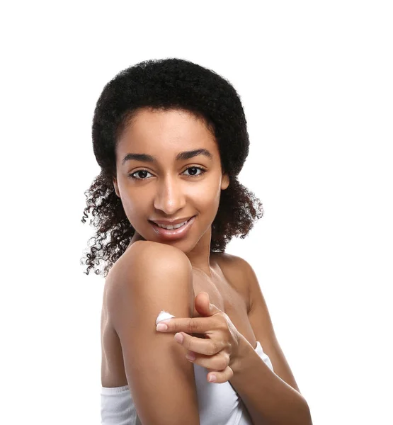Молодая афроамериканка наносит крем для тела на белом фоне — стоковое фото