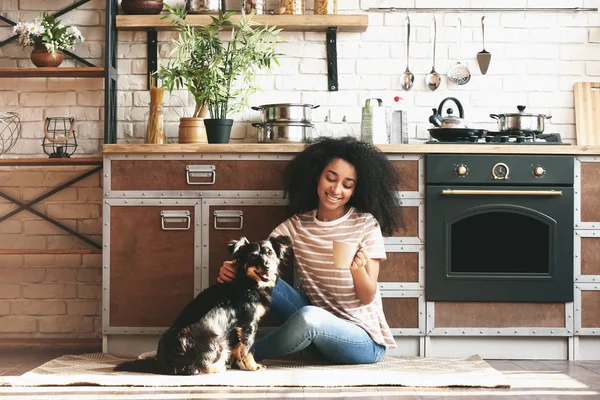 Mujer afroamericana con lindo perro divertido beber café en la cocina —  Fotos de Stock