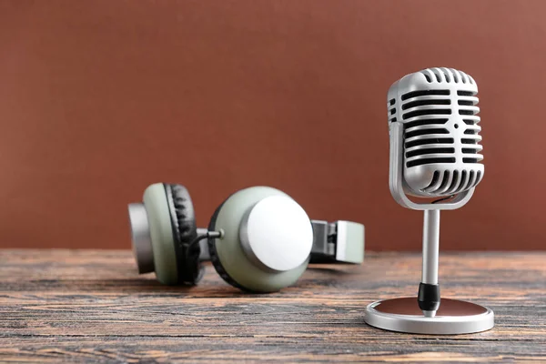 Micrófono retro y auriculares en la mesa contra el fondo de color —  Fotos de Stock